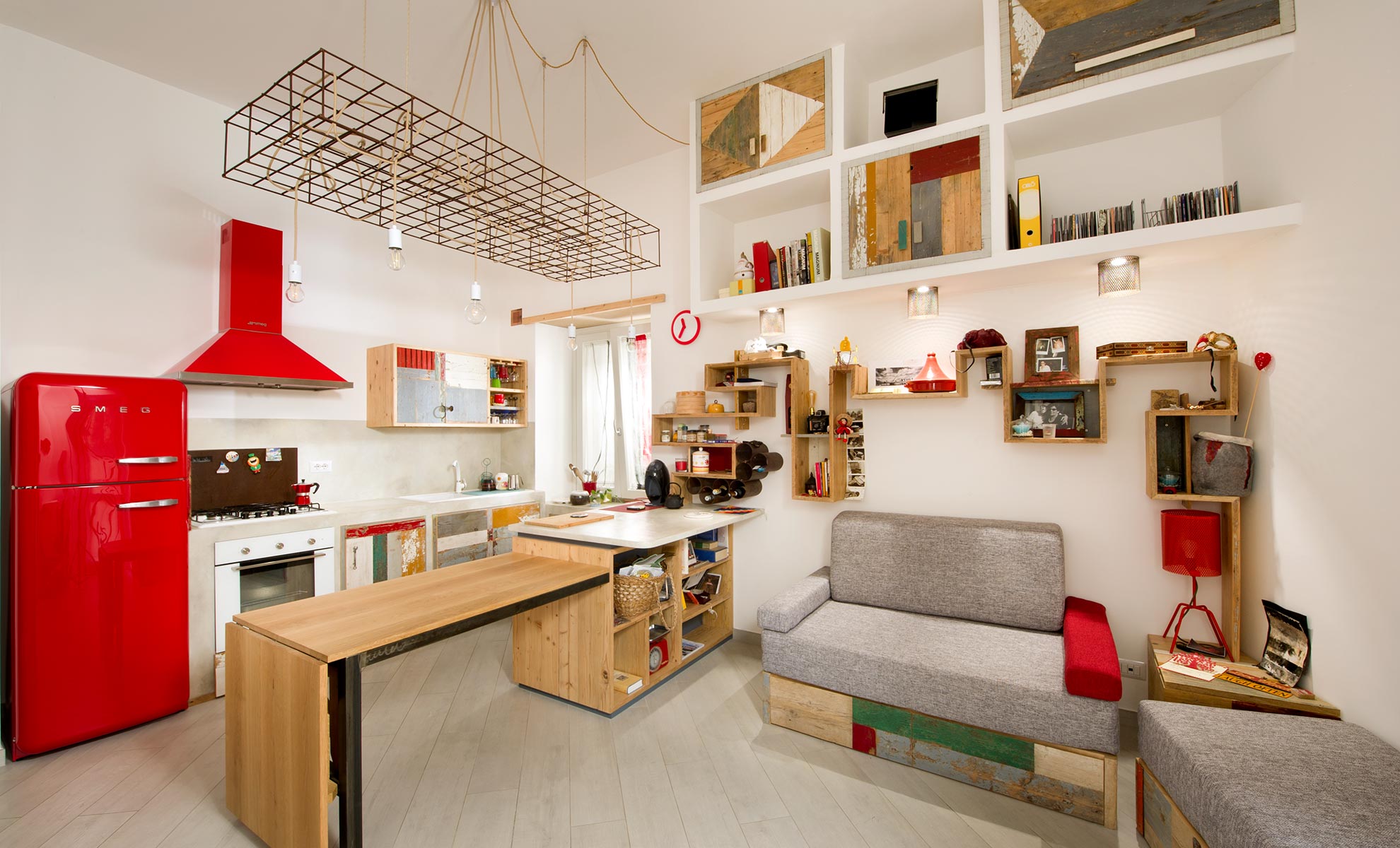 Arredamento per soggiorno in legno naturale, ferro e legno di recupero colorato. La foto ritrae un soggiorno open space con cucina stile industriale a vista